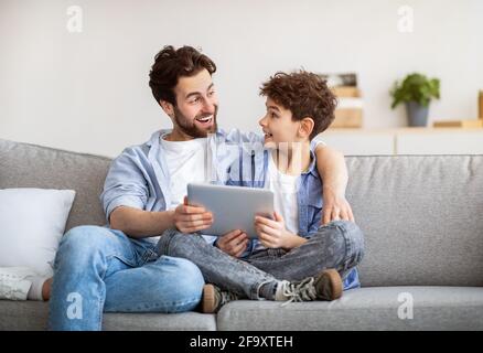 Familienwochenende. Vater und Sohn wurden mit einem Tablet-Computer excoted, surfte im Internet, während sie zu Hause Zeit miteinander verbrachten Stockfoto