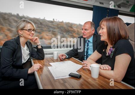 Gruppe von Personen, die ein Geschäftstreffen im Zug abhalten. Stockfoto