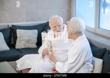 Reifes Paar in weißen Roben auf dem Sofa sitzen und Etwas besprechen Stockfoto