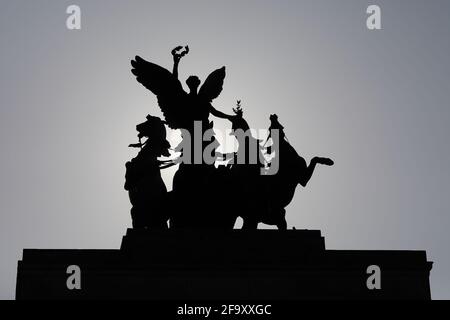 London, Großbritannien - 20. Apr 2021: Die bronzene Quadriga, die sich auf dem Wellington Arch in der Hyde Park Corner befindet, ist gegen die Morgensonne silhouettiert. Stockfoto