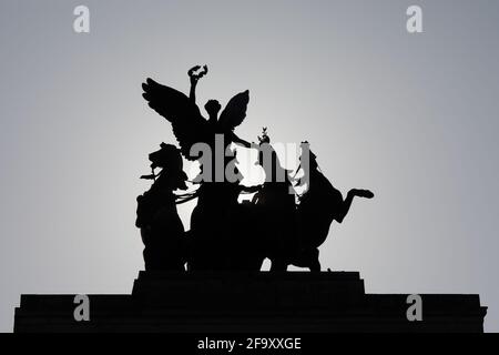 London, Großbritannien - 20. Apr 2021: Die bronzene Quadriga, die sich auf dem Wellington Arch in der Hyde Park Corner befindet, ist gegen die Morgensonne silhouettiert. Stockfoto