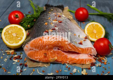 Großes Stück roten Fisch und Gemüse auf einem blauen Holztisch Stockfoto