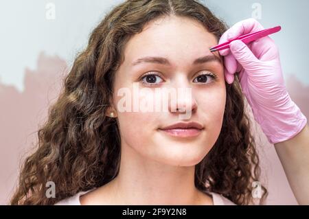 Augenbrauenmeister macht eine Augenbrauenkorrektur für eine junge Frau. Henna Augenbraue Färbung Verfahren in einem Schönheitssalon Stockfoto