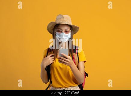 Weibliche Backpacker in Gesichtsmaske mit dem Smartphone Stockfoto