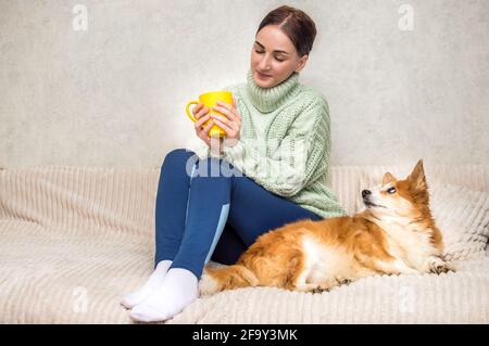 Junge Frau mit Hund auf dem Bett und Kaffee trinken Stockfoto