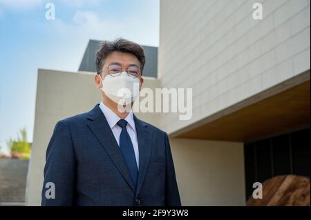 Ein asiatischer Geschäftsmann mittleren Alters in der Stadt, der eine Gesichtsmaske trägt. Stockfoto