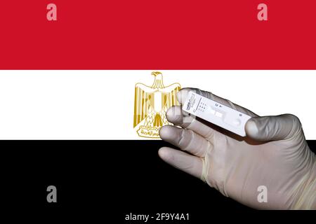 Eine Hand, die einen negativen antigenen Corona-Schnelltest in zeigt Vorderseite einer Flagge Ägyptens Stockfoto