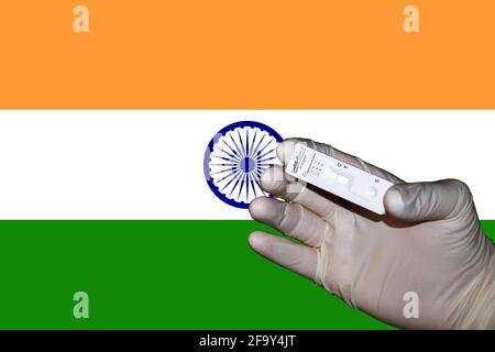 Eine Hand, die einen negativen antigenen Corona-Schnelltest in zeigt Vorderseite einer Flagge Indiens Stockfoto