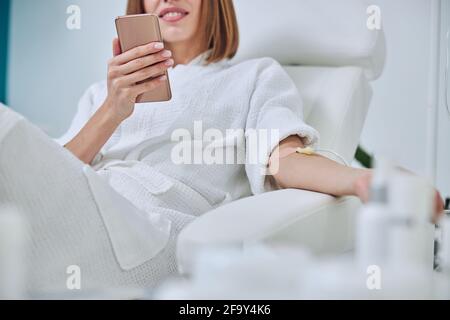 Schöne kaukasische Frau sitzt im Sessel während der Medizin Verfahren in Spa-Salon Stockfoto
