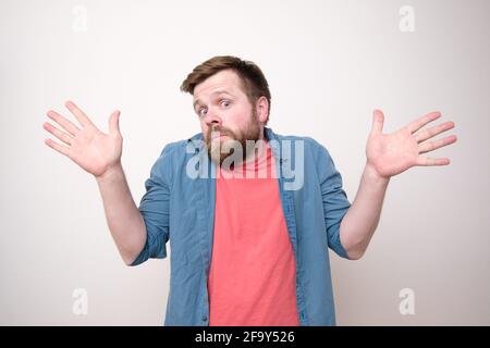 Überraschender bärtiger Mann in Verwirrung, er ist unschuldig und macht eine Geste mit Händen, offenen Handflächen, schaut auf die Kamera. Stockfoto