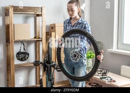 Eine Frau führt Wartungsarbeiten an seinem Mountainbike durch. Konzept der Befestigung und Vorbereitung des Fahrrads für die neue Saison Stockfoto