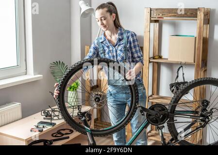 Eine Frau führt Wartungsarbeiten an seinem Mountainbike durch. Konzept der Befestigung und Vorbereitung des Fahrrads für die neue Saison Stockfoto