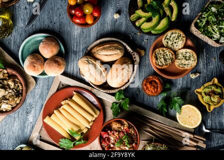 Aus dem Blickfeld einige verschiedene vegane Snacks, Beilagen, Dips wie Guacamole und einige andere Zutaten, um vegane Sandwiches auf einem grauen ru zuzubereiten Stockfoto