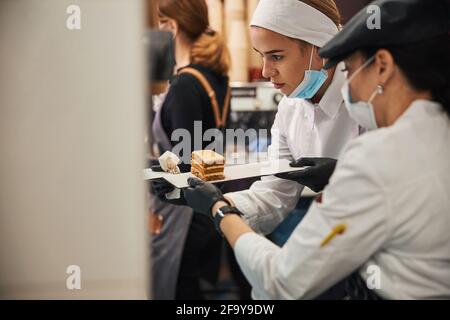 Zwei Küchenmitarbeiter bereiten Kuchen für die Kunden vor Stockfoto