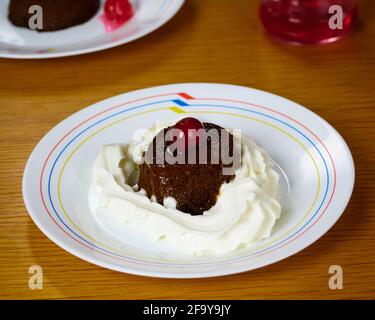 Creme Karamell Dessert oder Kaffee Flan mit Schlagsahne serviert Und eine Kirsche und dekoriert mit einem anderen Kaffee Flan und Ein Glas Kirschen und Holz Stockfoto