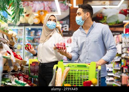 Muslimisches Paar, Das Lebensmittelgeschäft Macht Einkaufen Auswahl Von Bio-Gemüse Im Supermarkt Stockfoto