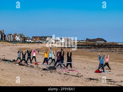 Menschen, die den Strand bei Sonnenschein mit Frauen im Yoga-Kurs genießen, North Berwick, East Lothian, Schottland, Großbritannien Stockfoto