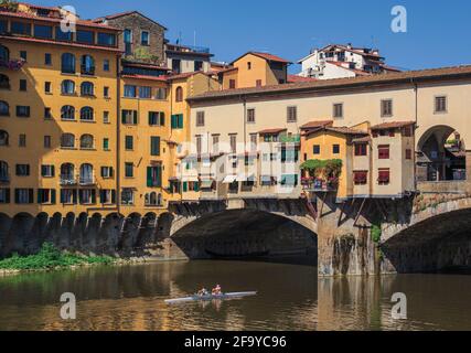 Florenz, Provinz Florenz, Toskana, Italien. Scullers, die unter der Ponte Vecchio oder der Alten Brücke am Arno vorbeifahren. Das historische Zentrum von Flo Stockfoto