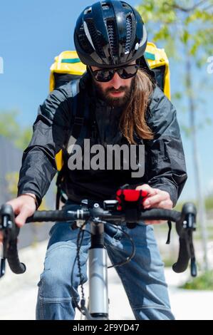 Männlicher Radfahrer mit Kuriertasche und Handy auf der Straße Stockfoto