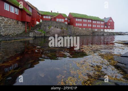 Thorshavn, Färöer-Inseln - 05.29.2017: Rote Holzhäuser mit weißen Fenstern im Regierungsbezirk Thorshavn, Färöer-Inseln. Reflexion im Waten Stockfoto