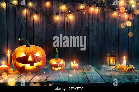 Halloween - Jack O' Lanterns - Kerzen und Fadenlichter Auf Holztisch Stockfoto