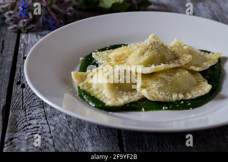 Ravioli gefüllt mit Kartoffeln und Karotten auf einem Bett Borretschpüree mit einer Prise Parmesan und schwarzem Käse Pfeffer Stockfoto