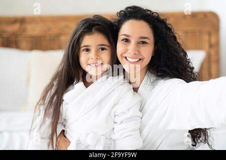 Schöne Mutter und Tochter in Bademänteln, die Selfie machen Stockfoto