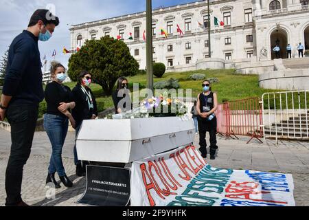 Lissabon, Portugal. April 2021. Bei einer Trauerfeier vor dem Palast der Republikanischen Versammlung in Lissabon führen Menschen mit Schutzmasken in der Nähe eines Sarges einen Ehrenakt durch.die Gruppe "Vigília Cultura e Artes" führt einen Straßenprotest durch, um Mahnwache für alle Fachleute des Kultursektors zu halten, die zurückgelassen wurden Durch die wenigen von der portugiesischen Regierung im Angesicht der COVID-19-Pandemie programmierten Notfallmaßnahmen. Kredit: SOPA Images Limited/Alamy Live Nachrichten Stockfoto