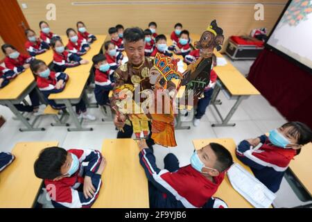 Shahe, Chinas Provinz Hebei. April 2021. Ein Künstler zeigt den Schülern der Mittelschule Nr. 6 in der Stadt Shahe, nordchinesische Provinz Hebei, am 21. April 2021 Schattenpuppen. Die Mittelschule hat lokale Künstler eingeladen, den Schülern das traditionelle Schattenspiel vorzustellen, um ihre Schüler besser mit dem immateriellen Kulturerbe vertraut zu machen. Quelle: Luo Xuefeng/Xinhua/Alamy Live News Stockfoto