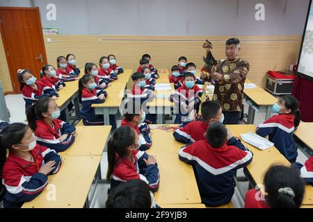 Shahe, Chinas Provinz Hebei. April 2021. Ein Künstler zeigt den Schülern der Mittelschule Nr. 6 in der Stadt Shahe, nordchinesische Provinz Hebei, am 21. April 2021 eine Schattenpuppe. Die Mittelschule hat lokale Künstler eingeladen, den Schülern das traditionelle Schattenspiel vorzustellen, um ihre Schüler besser mit dem immateriellen Kulturerbe vertraut zu machen. Quelle: Luo Xuefeng/Xinhua/Alamy Live News Stockfoto