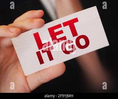 Nahaufnahme eines Geschäftsmannes, der eine Karte mit Text „LET IT GO“ hält, Geschäftskonzept Stockfoto