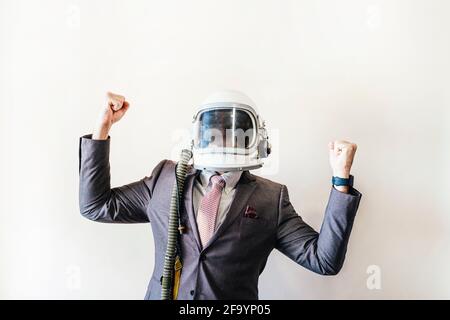 Geschäftsmann mit Astronautenhelm, der die beschwor raffenden Fäuste feiert Stockfoto