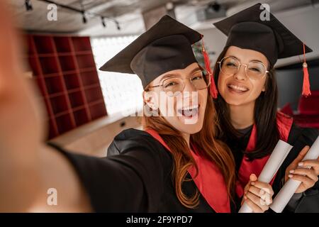 Aufgeregt und hübsche Studenten mit Diplom, Abschlussklasse 2021 Stockfoto