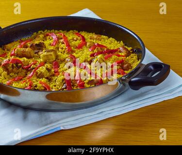 Traditionelle spanische Paella mit Meeresfrüchten, Schweinswürsten, Schweinerippchen und roten Paprika in der Pfanne. Draufsicht Stockfoto