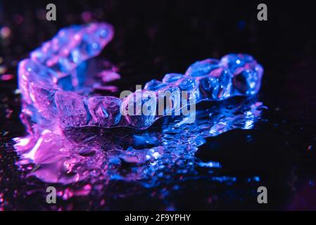 Transparente Ausrichter, Zahnhalter liegen auf Glas mit Wassertropfen auf schwarzem Hintergrund Stockfoto