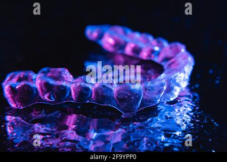 Transparente Ausrichter, Zahnhalter liegen auf Glas mit Wassertropfen auf schwarzem Hintergrund Stockfoto