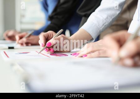 Hände von Mitarbeitern mit Stiften und Geschäftsgraphen mit finanziellen Anzeigen Stockfoto