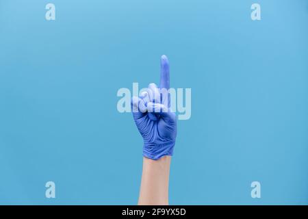Nahaufnahme der männlichen Hand in medizinischen Schutzhandschuhen mit Nein, isoliert auf blauem Studiohintergrund mit Platz für Werbung Stockfoto