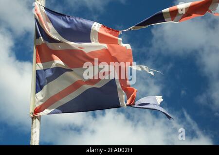 Alt und verblasst. Die Unionsflagge des Vereinigten Königreichs zerflattert und zerrissen, flattert und flattert im Wind gegen den Himmel. England, Großbritannien, Großbritannien. Stockfoto