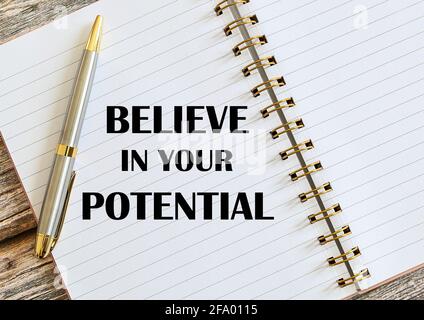 Draufsicht auf einen Stift mit „Believe in your Potential“ auf einem Notizbuch. Stockfoto