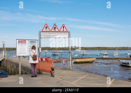 West Mersea Pier, Rückansicht einer Frau beim Lesen der Tafel am Eingang zum West Mersea Pier, Mersea Island, Essex, England, Großbritannien. Stockfoto