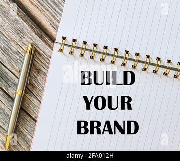 Draufsicht auf einen Stift mit „Build Your Brand“ auf einem Notizbuch. Stockfoto