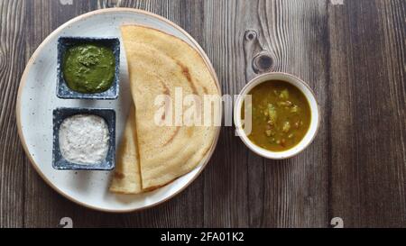 Dosa (Thin Pancake oder Crepe) ist eine südindische Mahlzeit, die mit sambhar und Kokosnuss-Chutney (Sauce) serviert wird, isoliert in einem anderen Hintergrund, einem anderen Stil Stockfoto