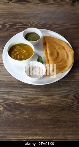 Dosa (Thin Pancake oder Crepe) ist eine südindische Mahlzeit, die mit sambhar und Kokosnuss-Chutney (Sauce) serviert wird, isoliert in einem anderen Hintergrund, einem anderen Stil Stockfoto