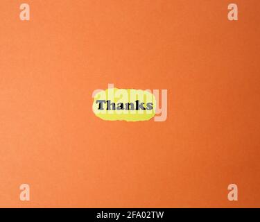Gelbes zerrissenes Papier auf orangefarbenem Hintergrund mit Dankesaufschrift Stockfoto