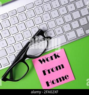 Draufsicht auf eine Tastatur und eine Brille mit der Arbeit von Haus auf einem Haftnotiz geschrieben Stockfoto