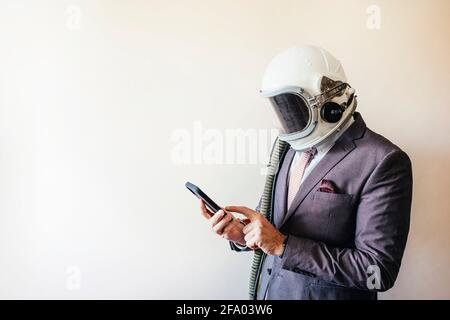 Geschäftsmann mit Astronaut-Helm mit Smartphone Stockfoto