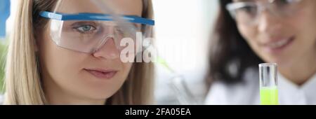 Wissenschaftlerinnen gießen chemische Flüssigkeit aus der Pipette in das Reagenzglas Im Labor Stockfoto