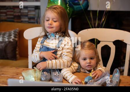 Zwei junge Schwestern packen Geburtstagsgeschenke über einen Zoom-Anruf aus An einen Verwandten während der Lockdown Covid 19 UK Stockfoto