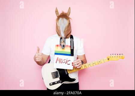 Mann in Pferdemaske mit Daumen nach oben und einem Schild Das sagt ¨Musik¨ Stockfoto